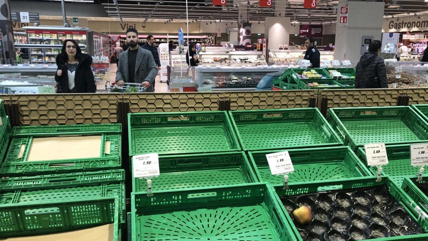 Scaffali ormai vuoti in un supermercato Coop (Ansa)