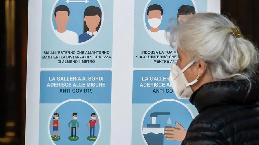 Una signora che indossa la mascherina mentre legge le regole anti Covid da rispettare