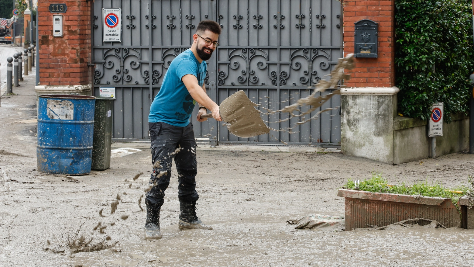 Un ragazzo rimuove con la pala acqua e fango su via San Mamolo, a Bologna