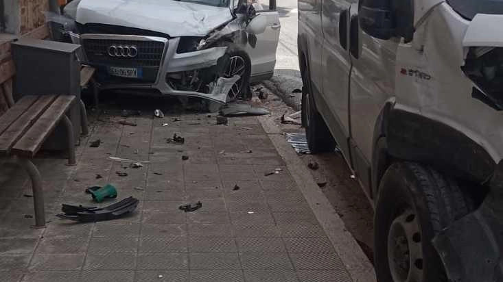 Auto contro furgone al semaforo. Audi sfonda vetrata di un negozio