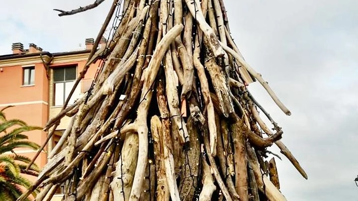 L’albero di Natale realizzato coi tronchi (di giorno e di sera, con le luminarie accese)