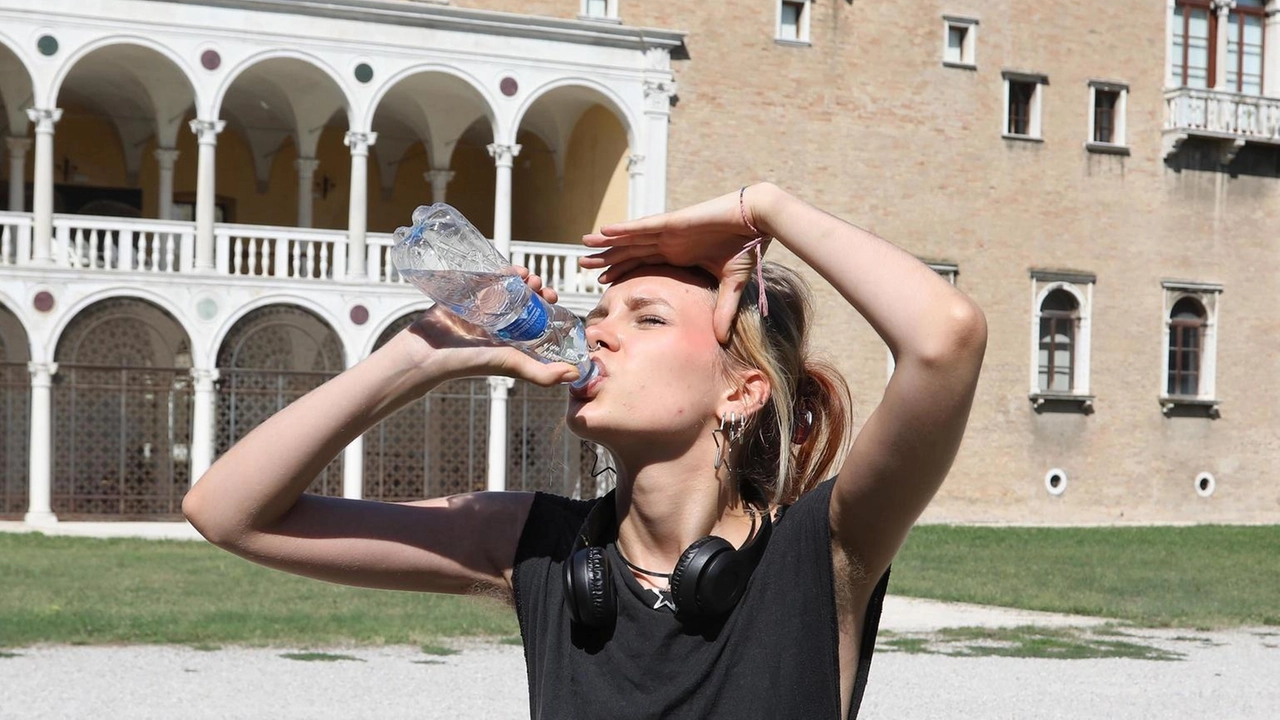 In una foto di qualche giorno fa, una ragazza si copre la testa dal sole e. si rinfresca con dell’acqua