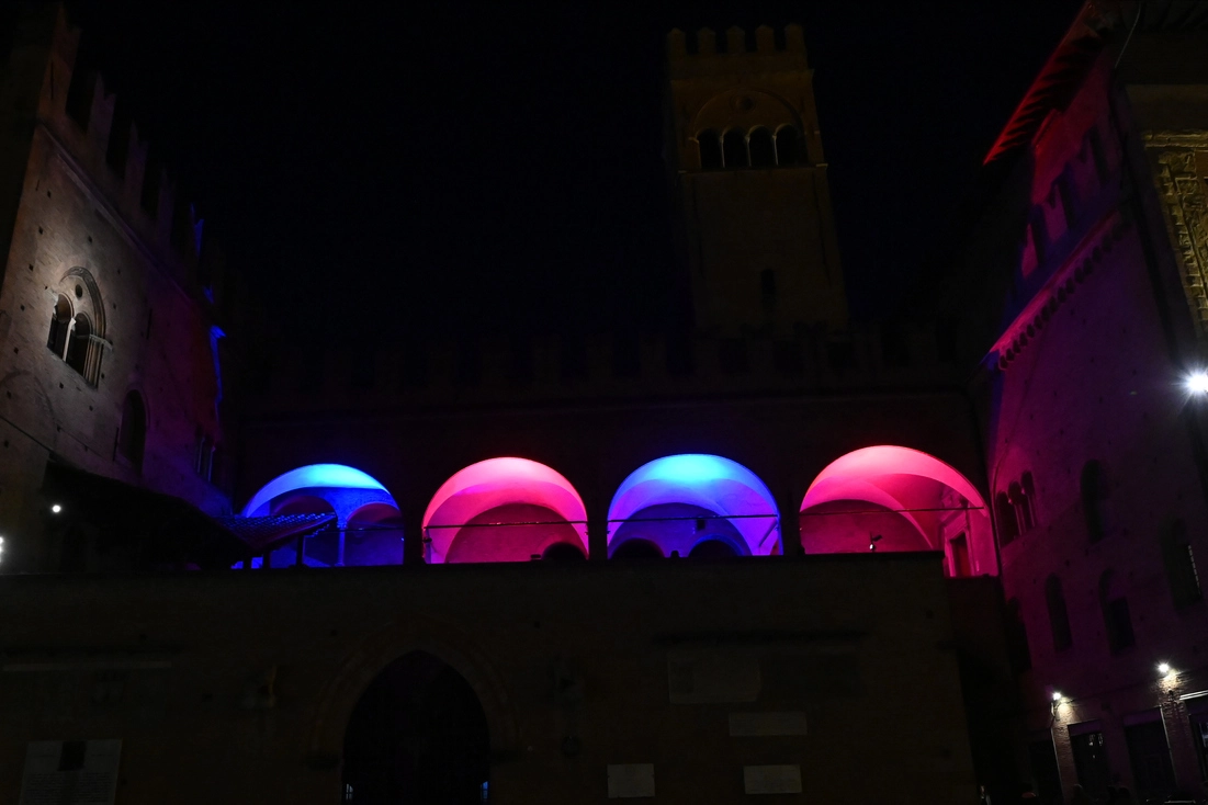 Palazzo Re Enzo illuminato di rosso e blu per supportare la squadra di Thiago Motta
