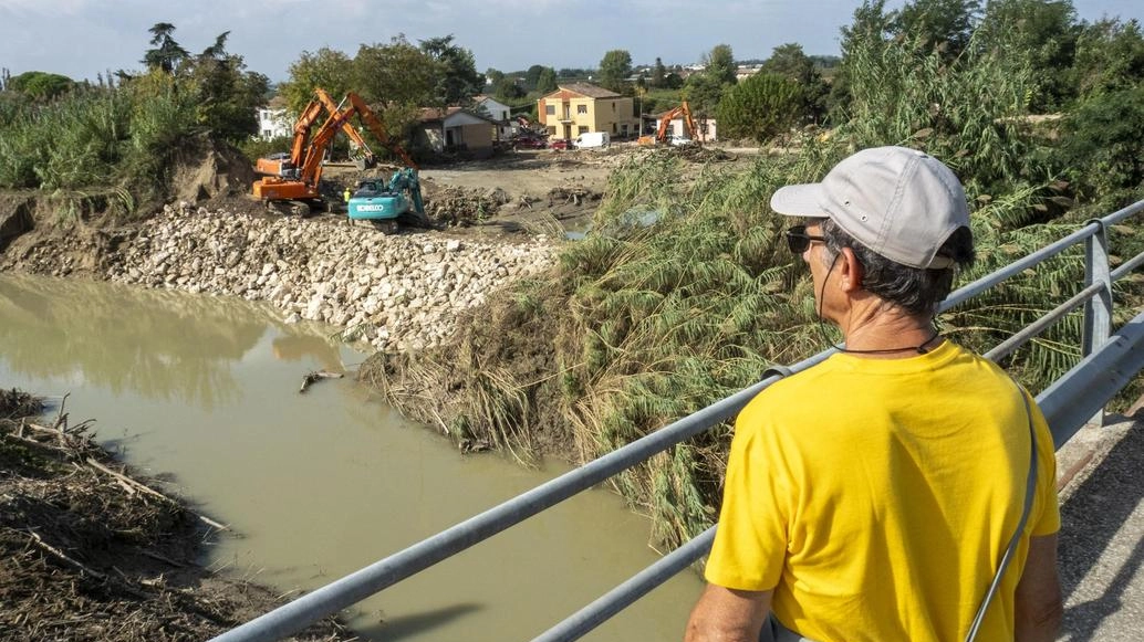 Un uomo osserva il Lamone a Traversara dopo il disastro, in una foto dei giorni scorsi. Nel tondo campi allagati