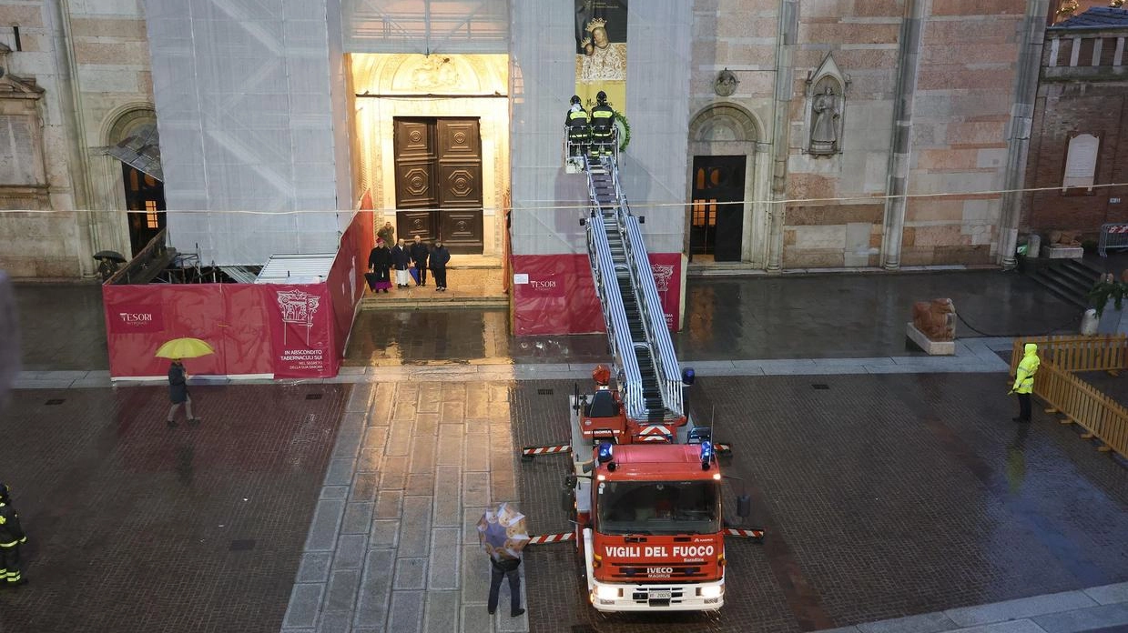 Nonostante il meteo avverso, l’accensione ha richiamato un po’ di curiosi assiepati sotto i portici. I vigili del fuoco appongono la corona alla Madonna.