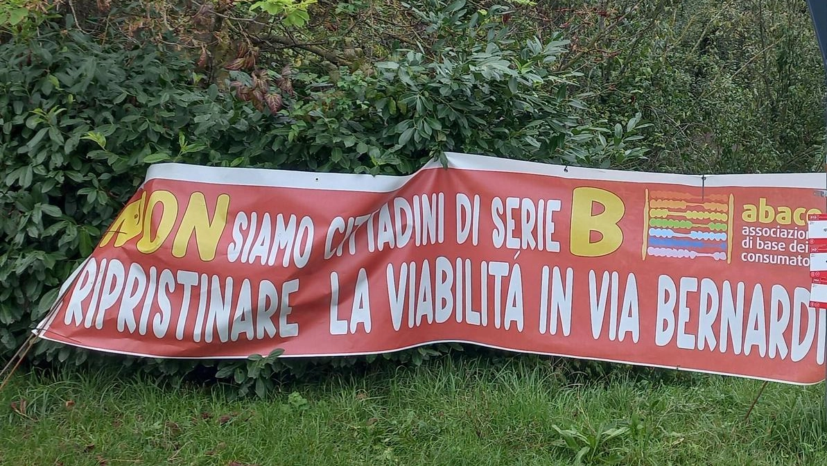 Lo striscione di protesta dei residenti di via Bernardi. Nel riquadro: Monica Cinti